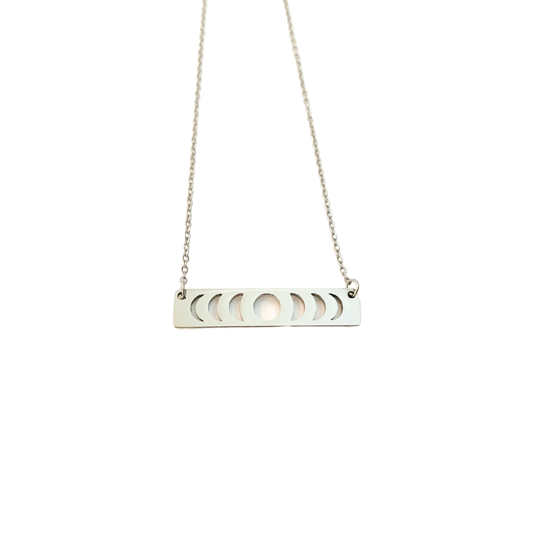 A silver necklace with a moon phase pendant on a chain, against a black background.