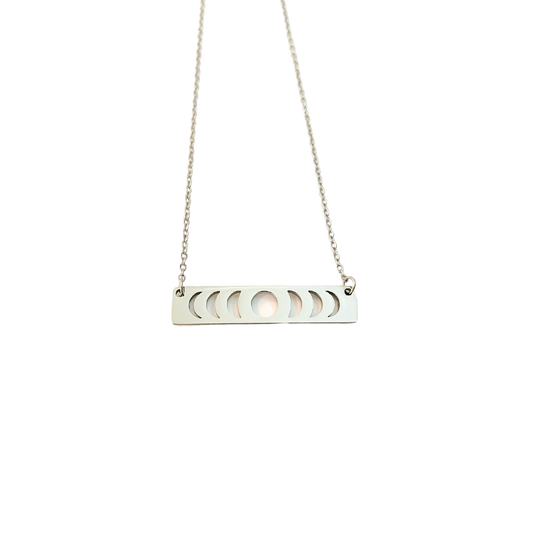 A silver necklace with a moon phase pendant on a chain, against a black background.