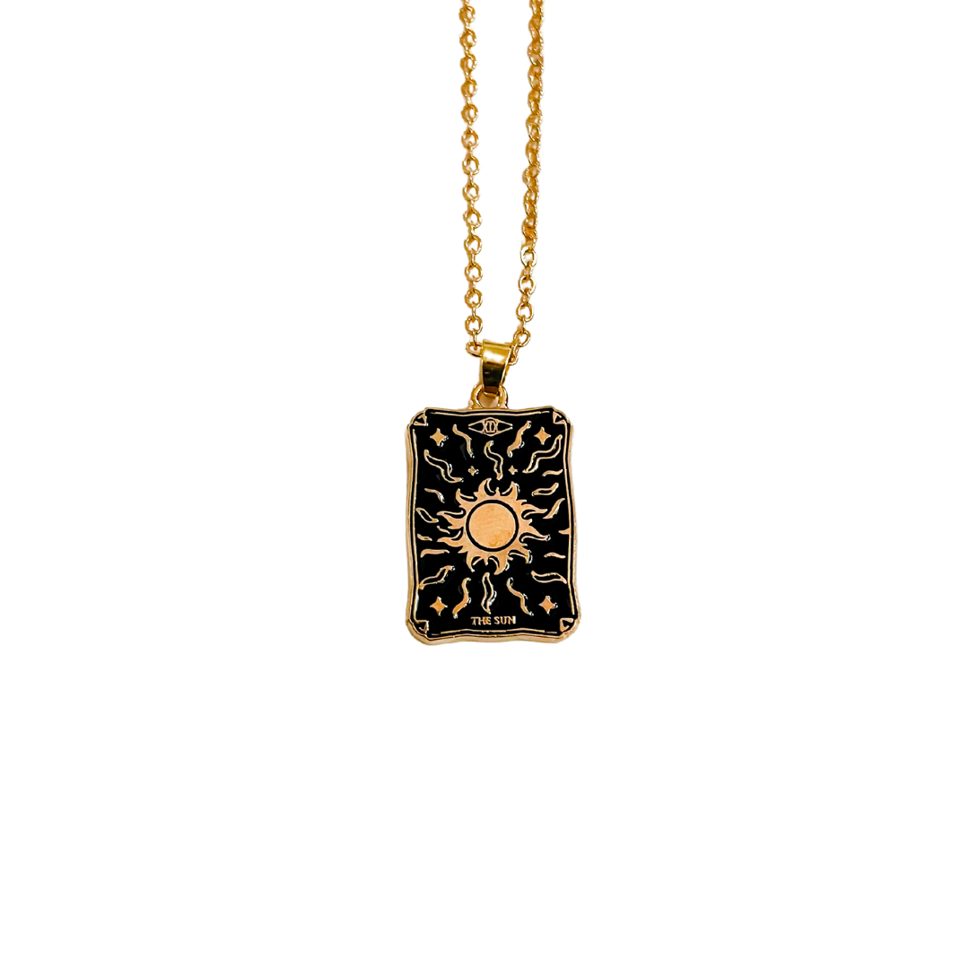 A gold-colored necklace with a sunburst tarot pendant on a chain.