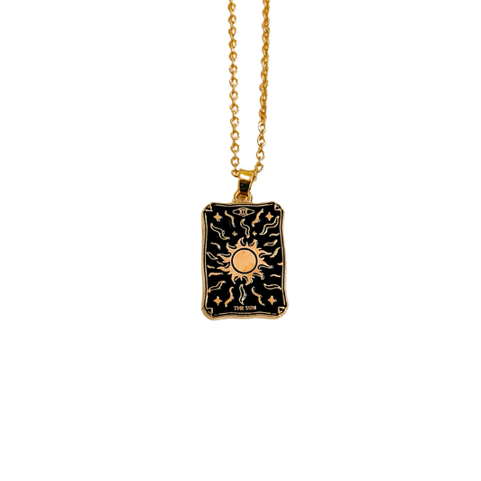A gold-colored necklace with a sunburst tarot pendant on a chain.